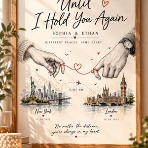 Puede incluir: Una lámina enmarcada titulada Until I Hold You Again con los nombres Sophia y Ethan. La ilustración muestra dos manos conectadas por un hilo rojo, con paisajes urbanos de Nueva York y Londres, una ruta de vuelo y fechas.