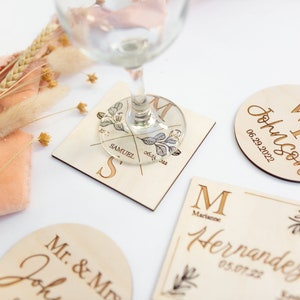 May include: Four wooden coasters with personalized names and dates. The coasters are in a variety of shapes and sizes, including a square, a circle, and a rectangle. The coasters are decorated with floral designs and the names and dates are engraved in a gold color.