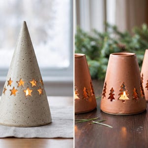 Può includere: Un alto portacandele conico in ceramica color bianco sporco maculato con intagli a forma di stella, insieme a tre portacandele in ceramica più corti color terracotta con intagli a forma di abete, ciascuno illuminato da una piccola candela.