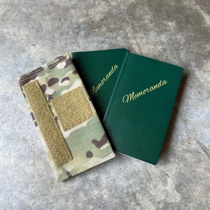 Pu&ograve; includere: Due quaderni verdi con la parola "Memoranda" stampata sulle copertine. Un quaderno &egrave; in una custodia di tessuto mimetico.