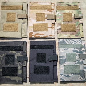 May include: Six different camouflage patterned notebook covers with velcro closures. The covers are made of a durable fabric and have a variety of colors and patterns.
