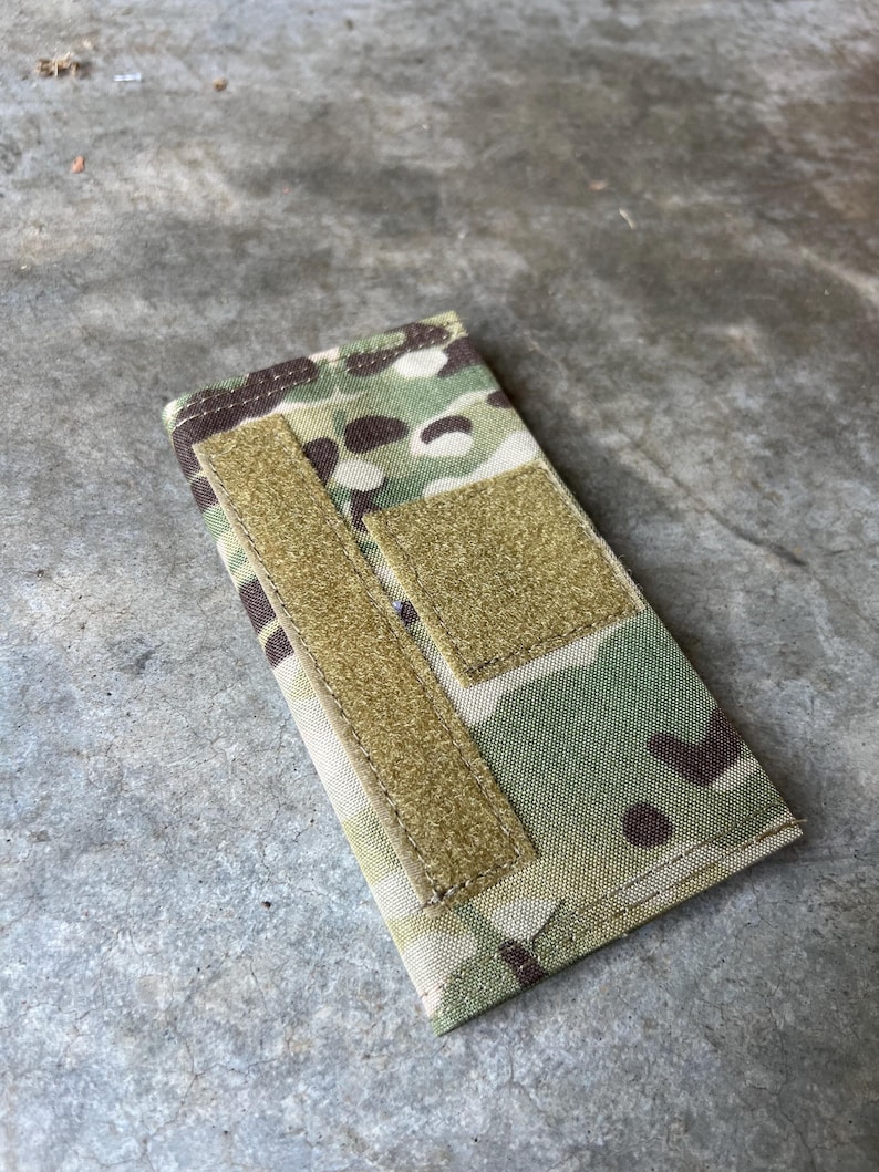 Pu&ograve; includere: Una piccola borsa mimetica con due chiusure a velcro. La borsa &egrave; realizzata in tessuto resistente e ha una combinazione di colori verde, marrone e beige.