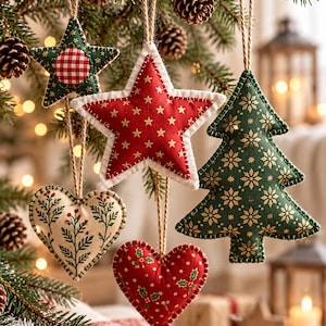 Op de afbeelding: Een set van vijf stoffen ornamenten hangend aan touwtjes. De set bevat twee sterren, één in rood met gouden sterren en één in groen met een rood ruitjespatroon in het midden, twee harten met bloemen- en hulstpatronen, en een groene boom met gouden sneeuwvlokken.