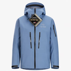 Può includere: Una giacca con cappuccio azzurra dotata di una cerniera frontale nera a tutta lunghezza, due tasche verticali sul petto con cerniere nere e una piccola tasca sulla manica. Il logo Arc'teryx è sul petto e un'etichetta Gore-Tex a forma di diamante pende dal colletto.