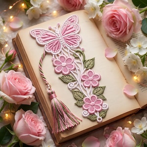 Può includere: Un segnalibro a forma di farfalla ricamato in rosa e bianco con motivi floreali, foglie verdi e una nappa multicolore rosa e verde attaccata da un cordoncino intrecciato, appoggiato sulle pagine aperte di un libro tra fiori rosa e bianchi.