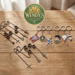 May include: A collection of metal accessories including dark silver chain rings with dagger, hook, and cross charms, alongside several keychains featuring colorful anime-style character figures, a spider emblem, and a red and white numbered tag.
