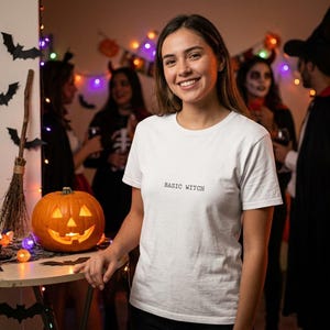 Può includere: Una t-shirt bianca a maniche corte con la scritta "BASIC WITCH" stampata in piccole lettere nere al centro del petto. La maglietta presenta un classico girocollo e un orlo dritto, realizzata in un tessuto bianco tinta unita.