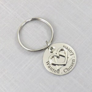 May include: Silver keychain with a heart charm and the words "Wanted. Chosen. Loved." engraved on a round tag.