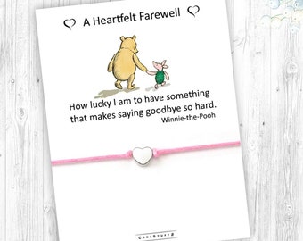 May include: A pink string bracelet with a silver heart charm. The bracelet has a card attached with a quote from Winnie-the-Pooh that reads: "How lucky I am to have something that makes saying goodbye so hard. Winnie-the-Pooh".