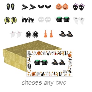 May include: A collection of Halloween-themed earrings in various designs, including coffins, bats, pumpkins, skulls, witch hats, and cauldrons. The earrings are displayed on a white background with a gold box and a card that says "choose any two".