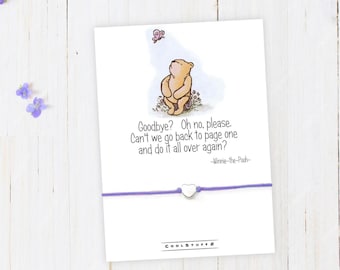 May include: A purple string bracelet with a silver heart charm. The card attached to the bracelet features a cartoon illustration of Winnie the Pooh and a butterfly. The card reads "Goodbye? Oh no, please. Can't we go back to page one and do it all over again? -Winnie-the-Pooh-"