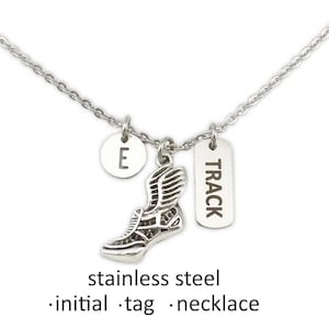 May include: A silver necklace with a running shoe charm, an initial "E" charm, and a tag that says "TRACK".