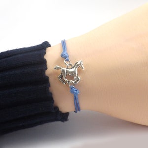 May include: A blue cord bracelet with a silver horse charm.