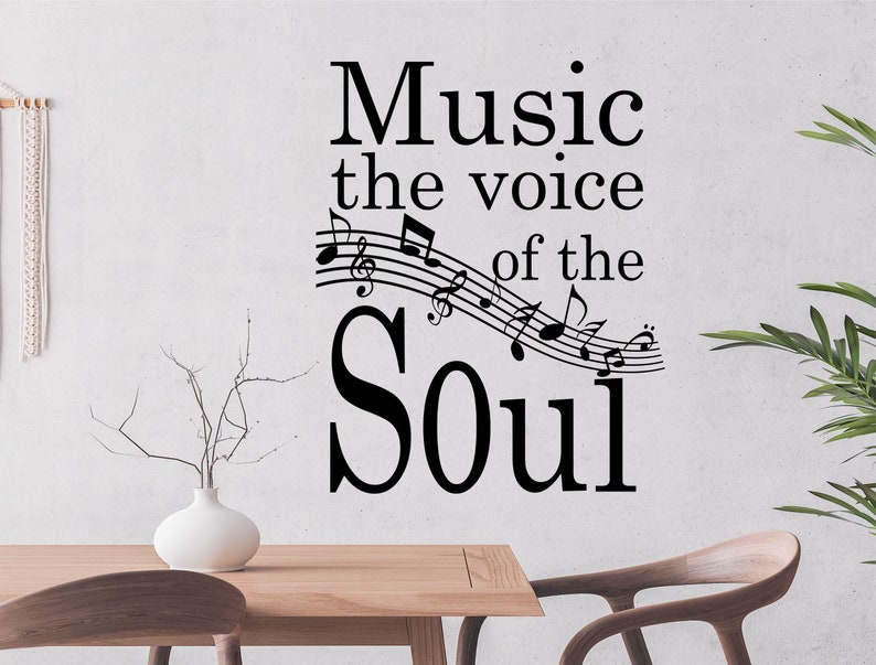 May include: Black and white wall decal with the text "Music the voice of the Soul" and musical notes. The decal is on a white wall with a wooden table and chairs in the foreground.