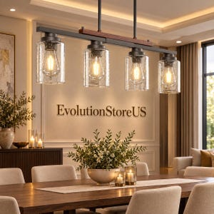 May include: A linear pendant light fixture featuring four cylindrical seeded glass shades suspended from a matte black metal frame with a dark wood accent bar. Each shade houses an Edison-style light bulb emitting a warm glow.