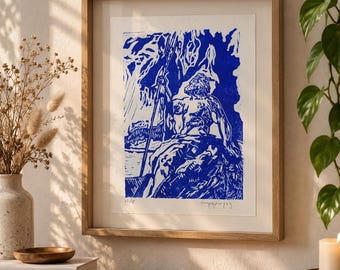 May include: A framed art print featuring a blue ink block print illustration of a figure holding a trident while standing on a rocky outcrop. The artwork is enclosed in a light-toned wooden frame with a white mat, displaying a numbered edition.