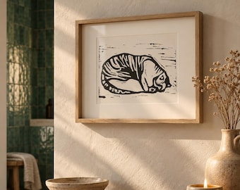 May include: A framed wall art print featuring a black ink block-print style illustration of a curled-up tiger on a white background. The artwork is enclosed in a light-toned wooden frame with a white mat border, displaying a textured artistic aesthetic.