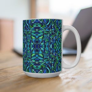 May include: A white ceramic mug featuring a repeating, symmetrical abstract pattern in shades of deep blue, teal, and bright green. The design consists of interconnected, flowing lines and organic shapes that wrap around the exterior surface.