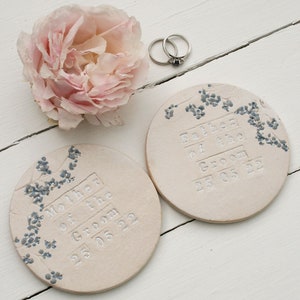 handmade white round ceramic coasters with blue and grey floral design with silver text mother or father of the groom and the date