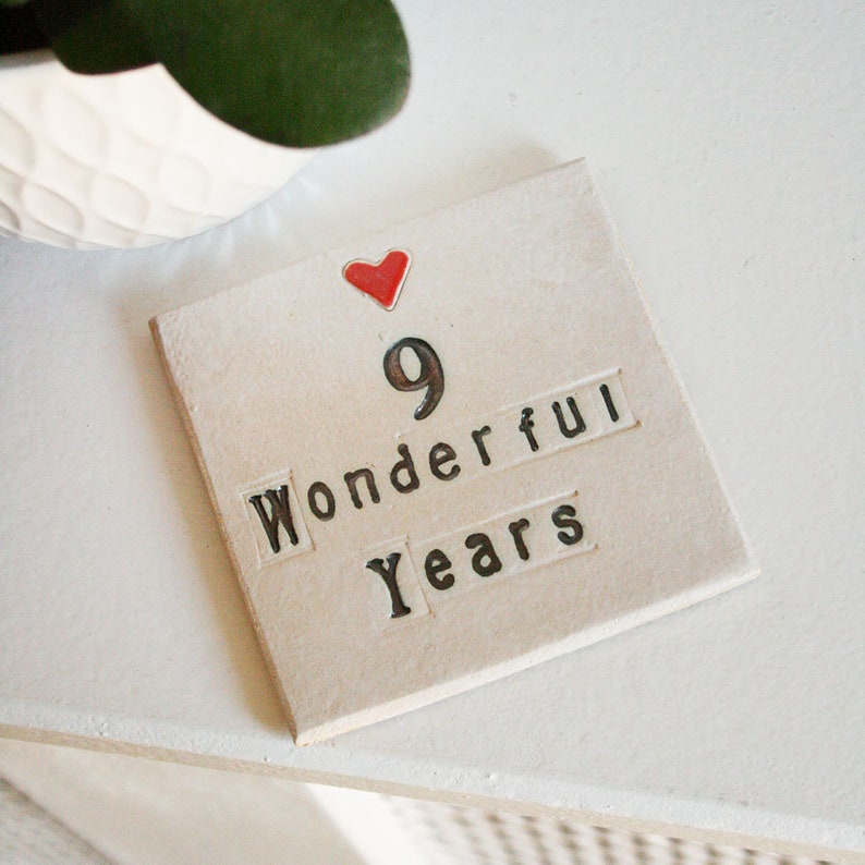 A square white coaster with a heart at the top with black text: 9 Wonderful Years
