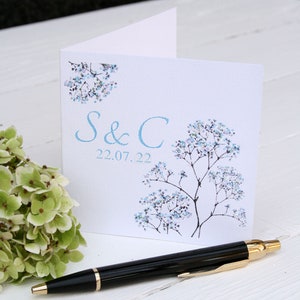 White square card with pretty blue flowers on either side. Blue text: INITIAL & INITIAL DATE
