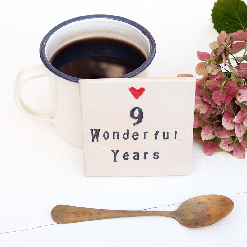 A square white coaster with a heart at the top with black text: 9 Wonderful Years