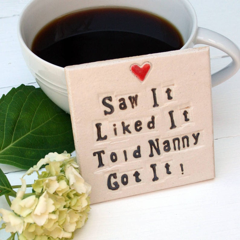 Square white coaster with red heart at the top and black text; Saw It Liked It Told Nanny Got It!