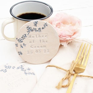 handmade white round ceramic coasters with blue and grey floral design with silver text or mother of the groom and the date