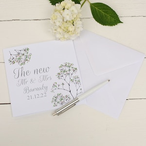 White square card with Pink and green flowers along the side with silver text: The New Mr & Mrs NAME DATE