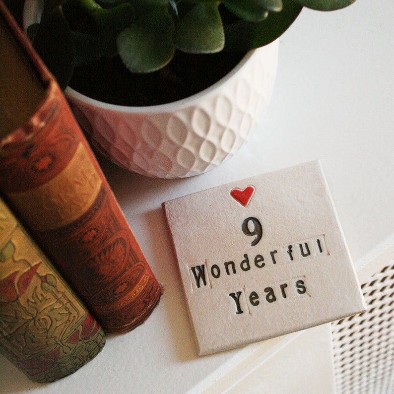 A square white coaster with a heart at the top with black text: 9 Wonderful Years