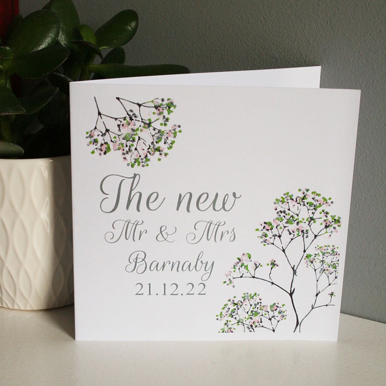 White square card with Pink and green flowers along the side with silver text: The New Mr & Mrs NAME DATE