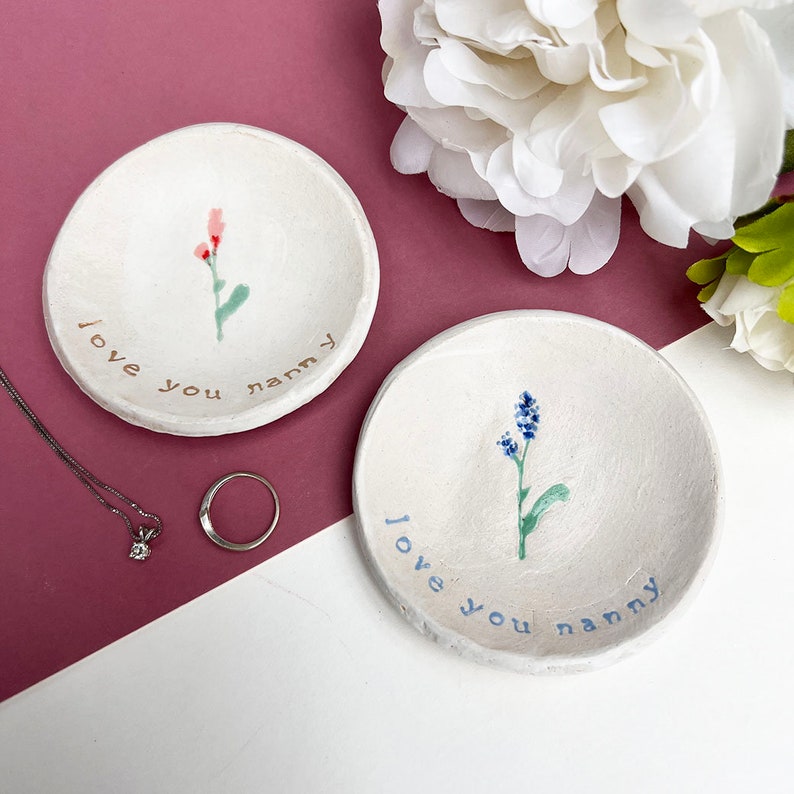 May include: Two white ceramic ring dishes with a floral design and the text "I love you nanny".