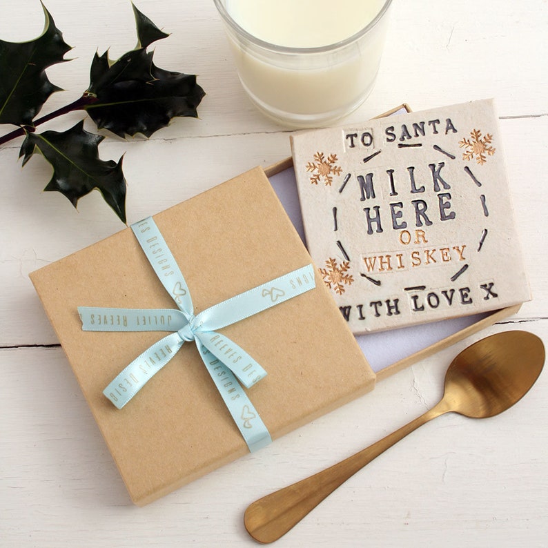 Square white coaster with gold snowflakes and black text: MILK HERE or whiskey, with love x