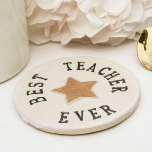 White round coaster with gold star in the centre and black text around the edge: BEST TEACHER EVER