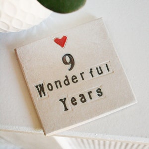 A square white coaster with a heart at the top with black text: 9 Wonderful Years