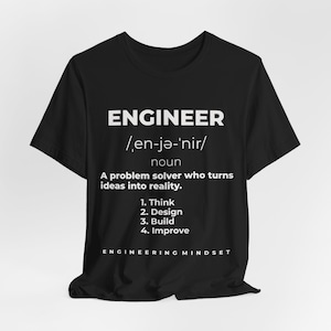 Könnte beinhalten: Ein schwarzes kurzärmeliges T-Shirt mit weißem Text, der das Wort ENGINEER als Problemlöser definiert, der Ideen in die Realität umsetzt, gefolgt von einer nummerierten Liste mit vier Schritten: 1. Think, 2. Design, 3. Build, 4. Improve und ENGINEERING MINDSET.