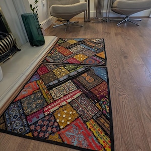 May include: Two rectangular floor rugs featuring a patchwork design of various colourful fabric squares. The rugs display intricate embroidery, small reflective mirror accents, and diverse patterns in shades of red, yellow, blue, and black.
