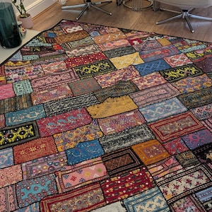 May include: A large rectangular patchwork quilt featuring a dense arrangement of multi-coloured fabric rectangles. Each section displays unique intricate patterns, floral motifs, and embroidery in shades of red, blue, yellow, and pink.