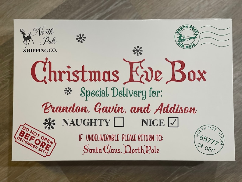 May include: White wooden box with a red and green Christmas Eve Box design. The box has a North Pole Shipping Co. logo and a North Pole Air Mail stamp. The text on the box reads "Christmas Eve Box", "Special Delivery for: Brandon, Gavin, and Addison", "Naughty", "Nice", "Do Not Open Before December 24th", and "If Undeliverable Please Return To: Santa Claus, North Pole".