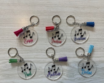 May include: Six clear acrylic keyrings with black musical notes and personalised names. Each keyring has a colourful tassel attached.