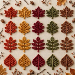 Op de afbeelding: Een verzameling van twintig gehaakte bladapplicaties gerangschikt in een raster, met vier verschillende bladvormen in vijf herfstkleuren: rood, geel, donkerrood, groen en bruin, geaccentueerd door verspreide kleine eikeltjes en takjes.