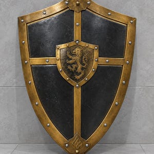 Puede incluir: Un escudo de tipo heráldico con una superficie de color gris carbón oscuro, un marco dorado metálico y un refuerzo en forma de cruz. Un emblema central dorado muestra un león en relieve, y toda la estructura está decorada con remaches plateados.