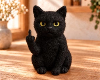 Peut inclure: Une figurine de chat noir en laine feutrée avec une fourrure texturée et des yeux jaune vif. Le chat est assis en position verticale avec sa patte droite levée, étendant son majeur dans un geste. La figurine a des oreilles pointues.