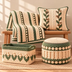 May include: A cream and dark green crochet set featuring a throw blanket with vertical bobble stripes, a square pillow with leaf and berry appliques, a rectangular storage basket with floral motifs, and a round ottoman with flower patterns.