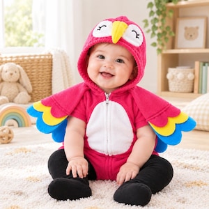 May include: A bright pink hooded fleece romper featuring a parrot design with a yellow beak, white face patches, and multi-coloured wing-shaped sleeves in yellow and blue. The garment has a front zip closure and a white belly panel.