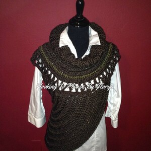 May include: A brown crocheted cowl with a green trim. The cowl is draped over a white shirt on a mannequin. The text "Hooking To Please By Gloria" is visible on the cowl.