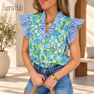 Puede incluir: Una blusa sin mangas con un vibrante estampado floral azul y verde, acentuada por mangas con volantes a rayas azules y blancas y un cuello en V a rayas a juego. La prenda se combina con pantalones cortos de mezclilla azul y un collar de cadena dorada.