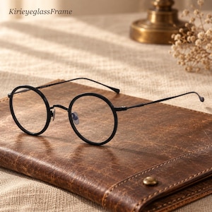 May include: Black round eyeglasses with thin metal frames and clear lenses. The text KirieyeglassFrame is visible in the upper left corner. The glasses feature a bridge and slender temples, showcasing a simple, circular design.