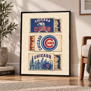 Puede incluir: Una impresión vertical enmarcada con tres ilustraciones de cajas de cerillas. La caja superior muestra un jugador de béisbol y el texto Chicago Cubs. La caja central muestra el logo de los Chicago Cubs. La caja inferior muestra la ciudad.
