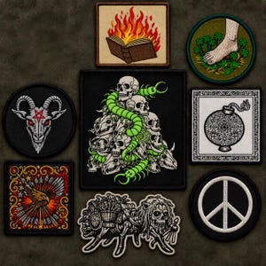 May include: A collection of eight embroidered patches featuring diverse designs: a burning book, a foot in clover, a goat head with a pentagram, a stack of skulls with a green centipede, a bomb, an eagle with arrows, and a peace sign.